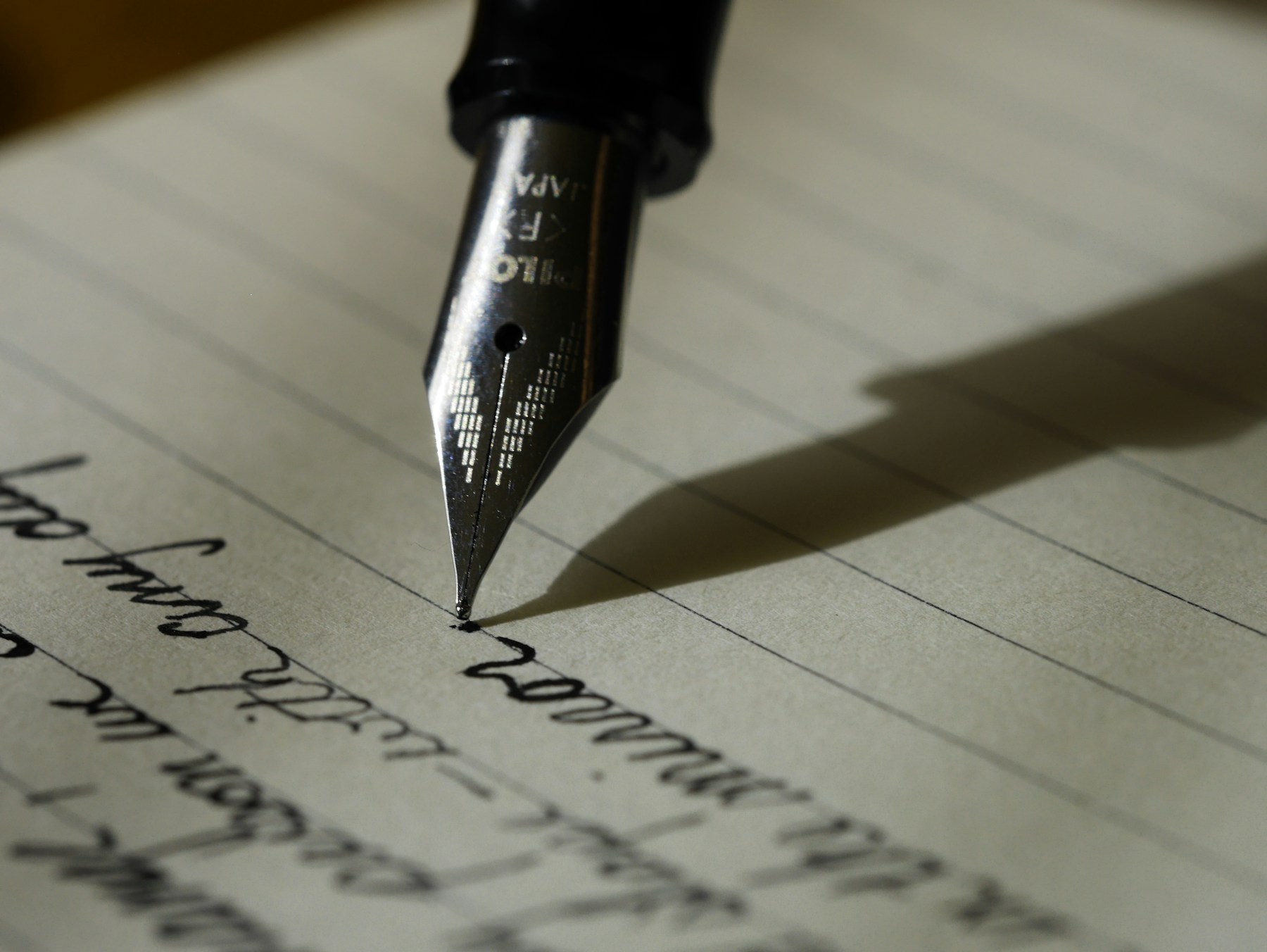 A fountain pen writing on lined paper